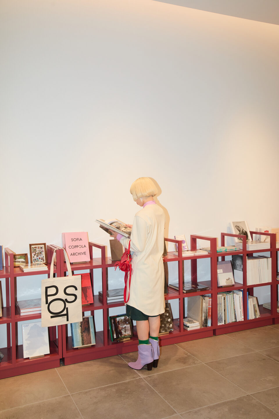 アオイヤマダさんがブックシェルフで写真集を手に取り閲覧するシーン