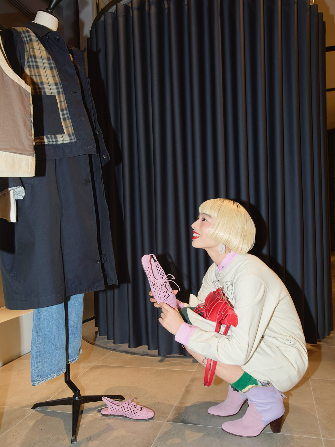 アオイヤマダがショップでマネキンを見ながらピンクのシューズを手にする
